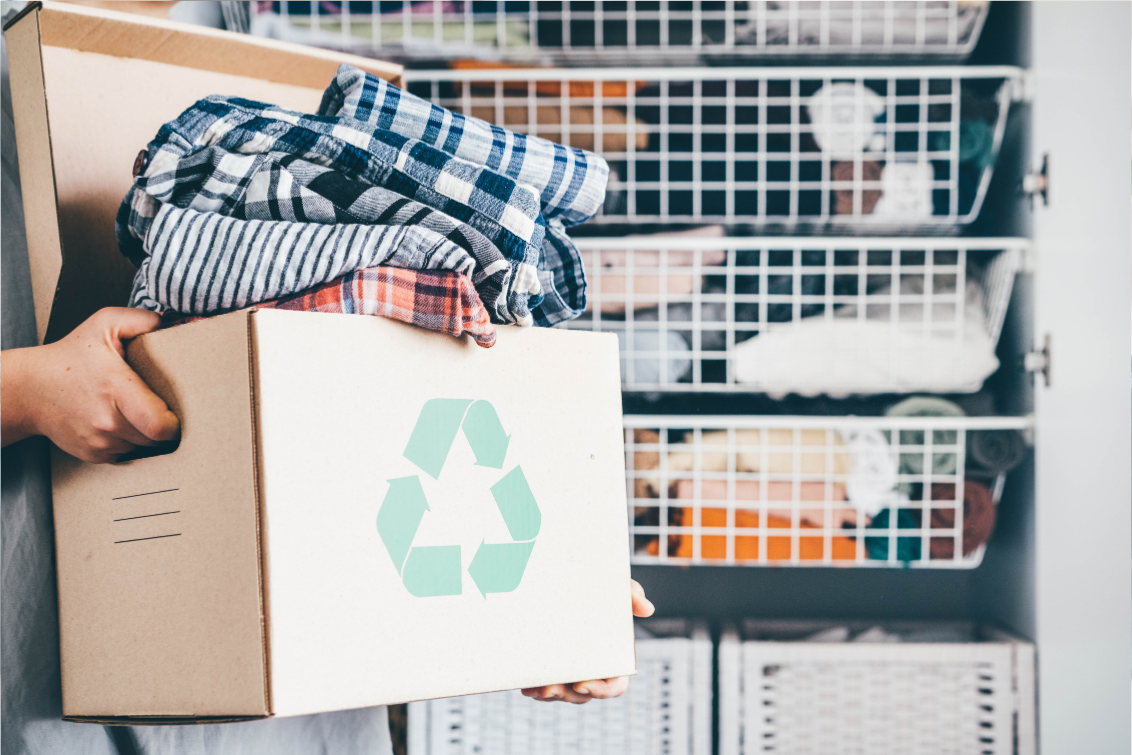 A person holding a recycling box filled with fabrics intended for an upcycling program