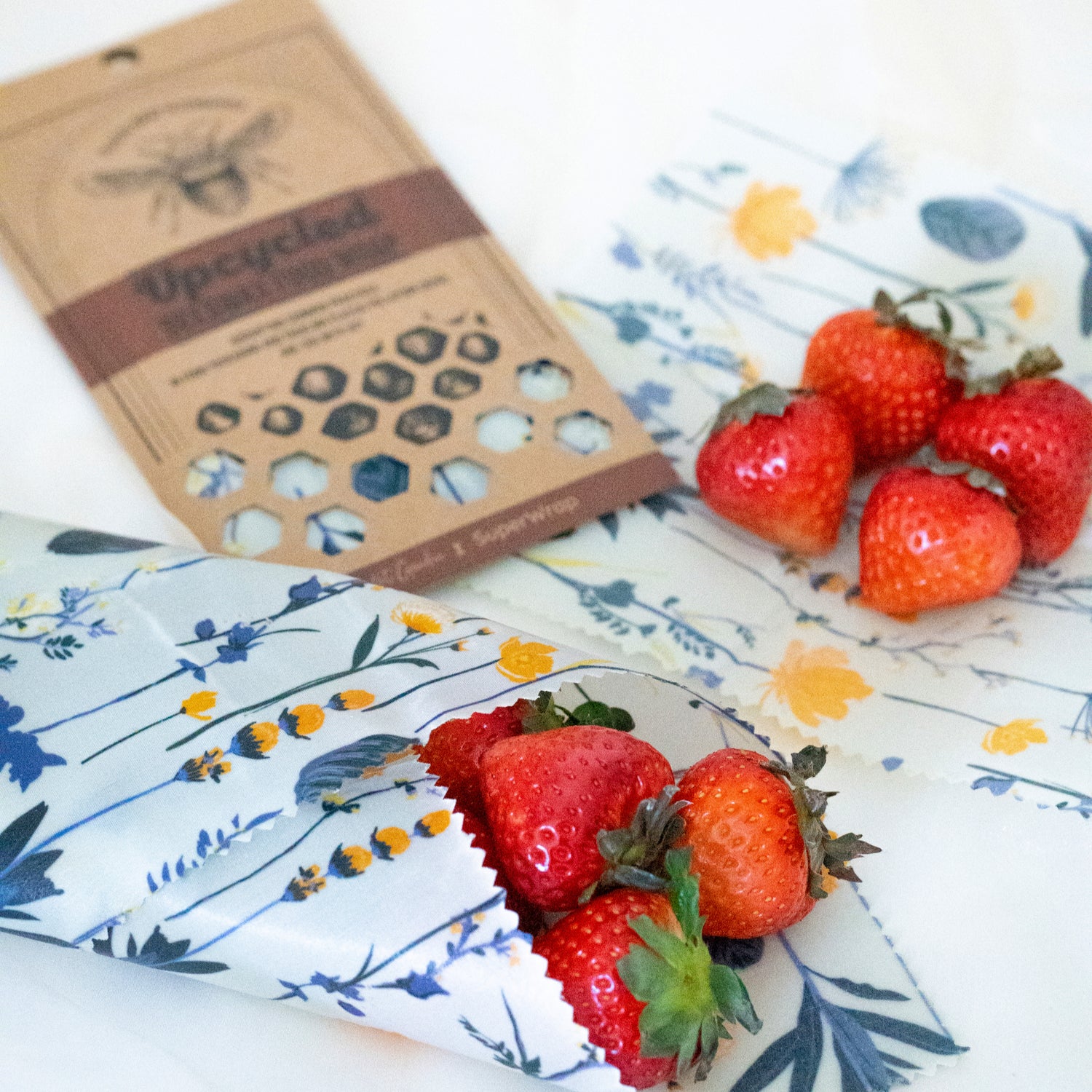Fresh strawberries partially wrapped in Superwrap’s upcycled beeswax wrap in the ‘Golden Petal’ design