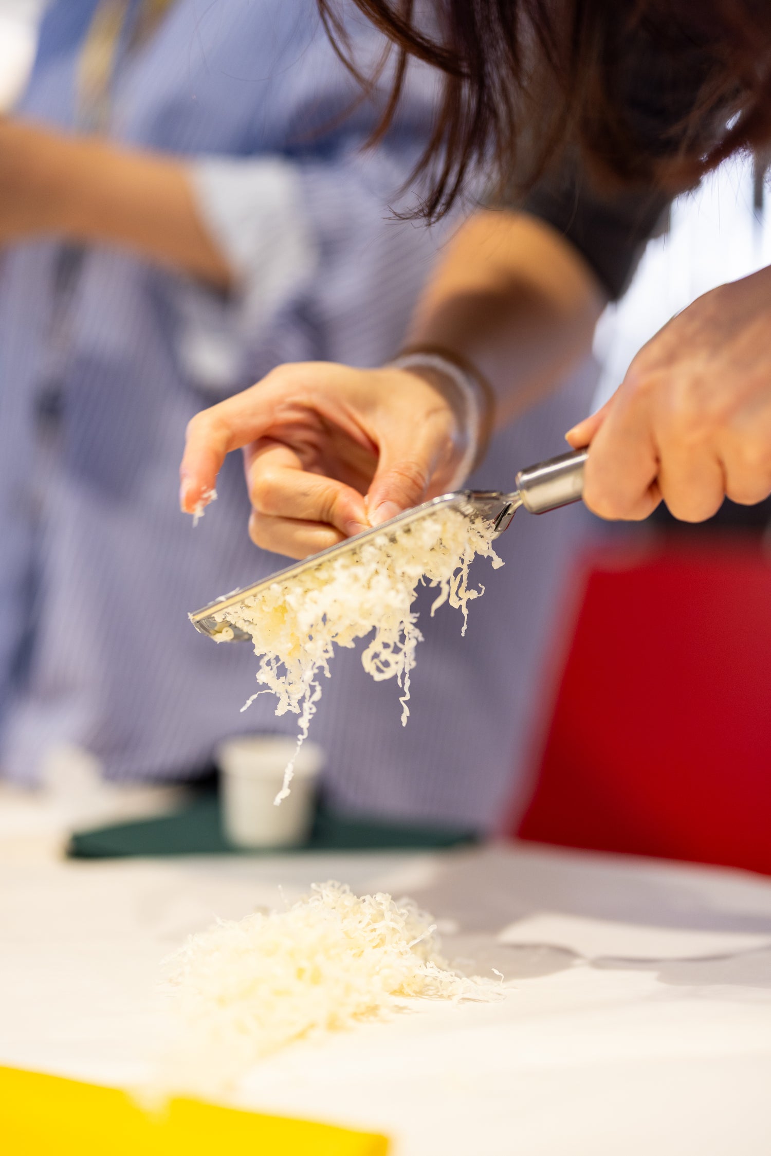 Hands grating beeswax over a yellow fabric during Superwrap’s DIY beeswax wrap workshop