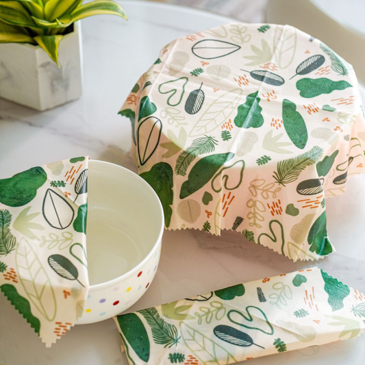 A white bowl with colorful polka dots partially covered in Superwrap’s upcycled beeswax wrap in the ‘Leafy Forest’ design